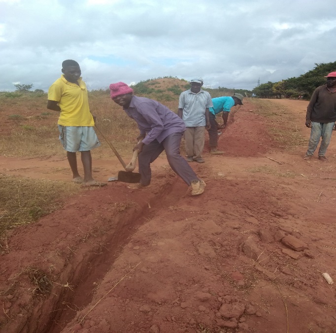 Headteacher and villagers digging trench.